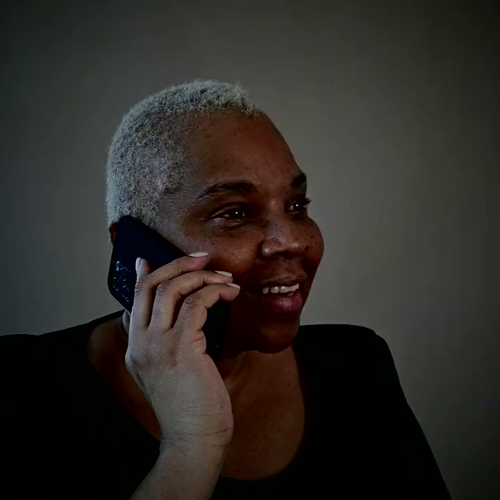 A woman laughing on a phone call.